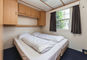 Gezellige slaapkamer met dubbel bed, opbergkasten en raam bij Bungalette basic + hot tub in Holiday Park Mölke.