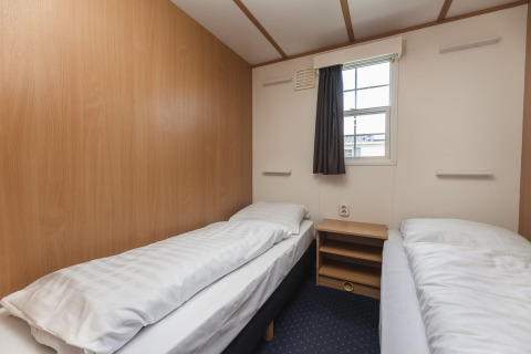 Simple bedroom with two single beds at Bungalette basic + hot tub in Holiday Park Mölke, Netherlands.