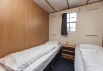 Eenvoudige slaapkamer met twee eenpersoonsbedden in Bungalette basic + hot tub bij Holiday Park Mölke, Nederland.