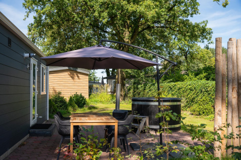 Terrasse der Bungalette basic + Hot Tub im Holiday Park Mölke, Niederlande, mit Schirm und Sitzbereich.