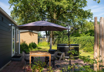 Terrasse der Bungalette basic + Hot Tub im Holiday Park Mölke, Niederlande, mit Schirm und Sitzbereich.