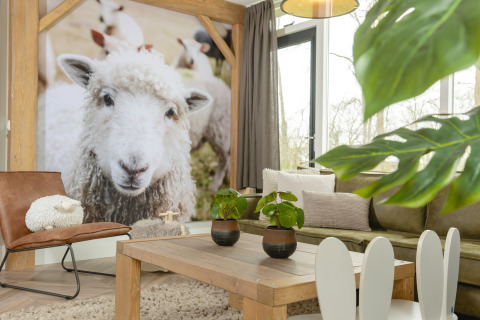 Sala de estar en el bungalow infantil de Holiday Park Mölke, Países Bajos, con foto gigante de oveja.