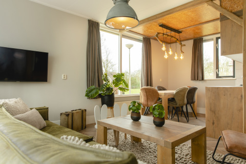 Salon moderne et lumineux du bungalow Baby & children au Holiday Park Mölke, Pays-Bas, avec coin repas.