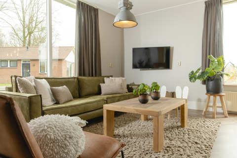 Lyst og moderne opholdsstue i Baby & children bungalow, Holiday Park Mölke, med grøn sofa og træbord.