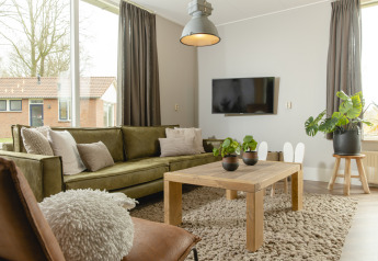 Lichte moderne woonkamer in Baby & children bungalow, Holiday Park Mölke, Nederland, met groene bank.