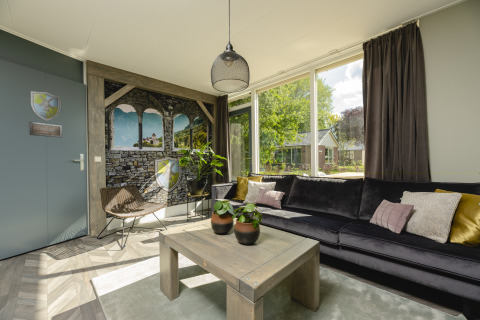 Hyggelig stue i Baby & children bungalow ved Holiday Park Mölke, med stor sofa og store vinduer.