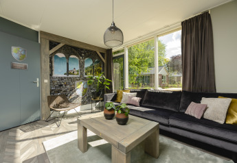 Cozy living room in the Baby & children bungalow at Holiday Park Mölke, Netherlands, with large windows.