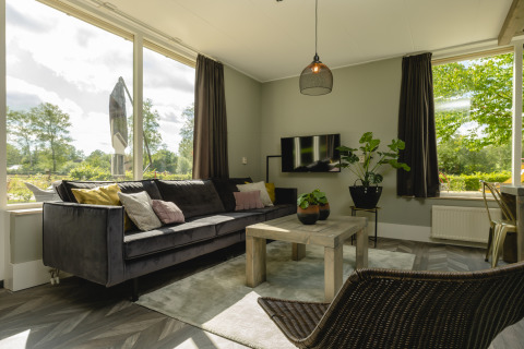 Lys stue i Baby & børn bungalow på Holiday Park Mölke, Nederlandene, med stor sofa og udsigt.