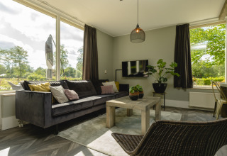 Bright living room in Baby & Children bungalow at Holiday Park Mölke, Netherlands, with sofa and views.