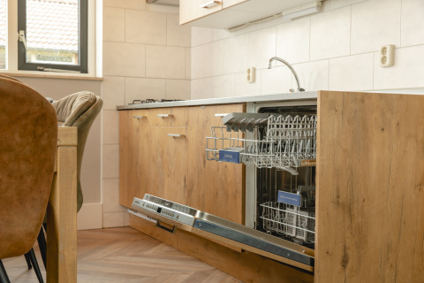 Lavavajillas integrado en una cocina moderna de madera en Baby & children bungalow, Holiday Park Mölke, Países Bajos.