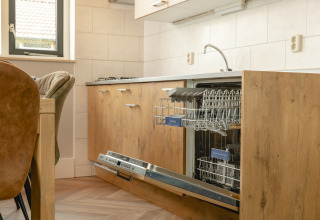 Built-in dishwasher in a modern wood-finish kitchen at Baby & children bungalow, Holiday Park Mölke, Netherlands.