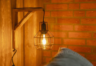 Rustic wall lamp with wire cage and warm glow in Baby & Children Bungalow at Holiday Park Mölke, Netherlands.
