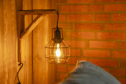 Rustikale Wandleuchte mit Drahtschirm und warmem Licht im Baby & Children Bungalow, Holiday Park Mölke.