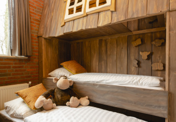 Chambre d’enfants avec lits superposés en bois et singe en peluche au Holiday Park Mölke, bungalow enfants.