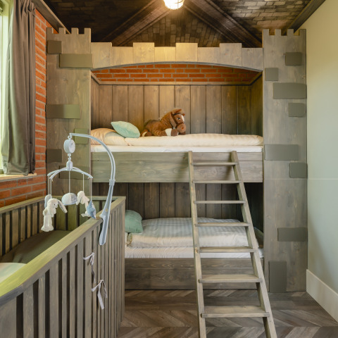 Habitación infantil con litera estilo castillo, cuna y peluche en Holiday Park Mölke, Países Bajos.