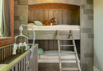 Habitación infantil con litera estilo castillo, cuna y peluche en Holiday Park Mölke, Países Bajos.