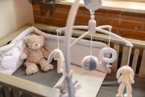 Cuna de bebé con osito de peluche y móvil, bungalow infantil acogedor en Holiday Park Mölke, Países Bajos.