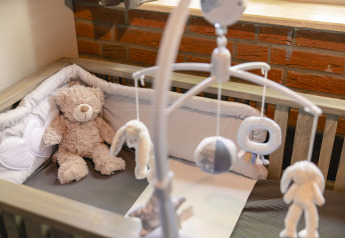 Baby krybbe med blød bamse og uro, hyggeligt interiør i børnebungalow på Holiday Park Mölke, Holland.