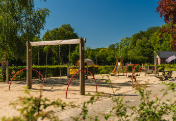 Speelplein bij Baby & Children bungalow, Holiday Park Mölke, Nederland, met schommels en glijbaan.