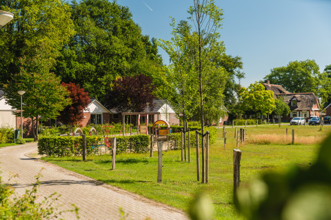 Udsigt over hytter og legeplads ved Baby & children bungalow i Holiday Park Mölke, Nederlandene, på en solrig dag.