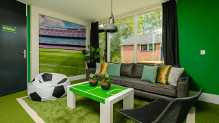 Habitación tipo lodge temática de fútbol en el estadio FC Mölke en Holiday Park Mölke, Países Bajos, con decoración verde.