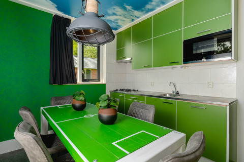 Keuken in de FC Mölke stadion lodge, met groene kasten en een eettafel als voetbalveld.