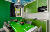 Unique kitchen at the FC Mölke stadium lodge, with green cabinets and a football field themed dining table.