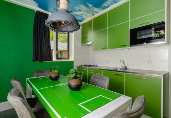 Keuken in de FC Mölke stadion lodge, met groene kasten en een eettafel als voetbalveld.