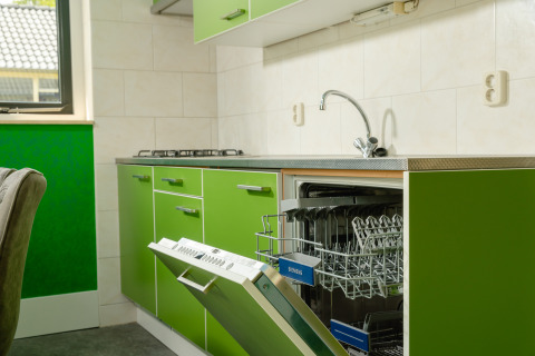 Green kitchen in the FC Mölke stadium lodge with dishwasher open at Holiday Park Mölke in the Netherlands.