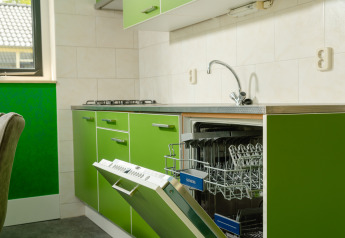 Green kitchen in the FC Mölke stadium lodge with dishwasher open at Holiday Park Mölke in the Netherlands.