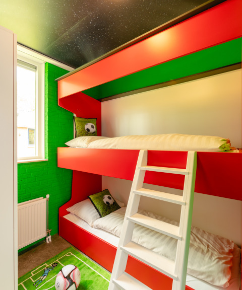 Football-themed room with red bunk beds, green decor, at FC Mölke Stadium lodge, Holiday Park Mölke.
