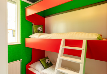 Football-themed room with red bunk beds, green decor, at FC Mölke Stadium lodge, Holiday Park Mölke.