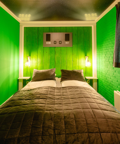 Slaapkamer met groene muren, dubbel bed en sportthema bij FC Mölke stadium in Holiday Park Mölke.