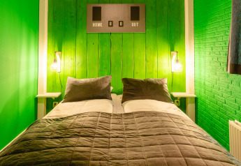 Camera da letto con pareti verdi, letto matrimoniale e decorazioni sportive al FC Mölke stadium, Holiday Park Mölke.