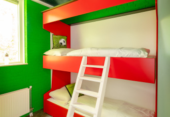 Kids' football-themed room with bunk bed, green walls, play carpet, and window at Holiday Park Mölke, Netherlands.