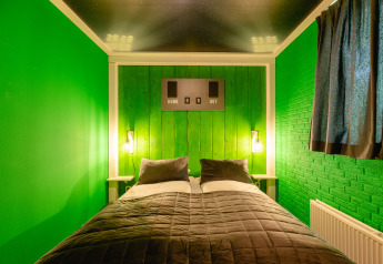 Slaapkamer in de FC Mölke stadion lodge op Vakantiepark Mölke, Nederland, met groene muren en scoreborddecoratie.