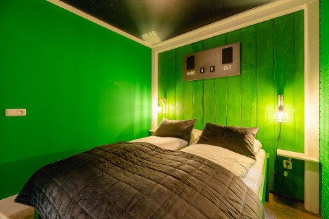 Slaapkamer in de FC Mölke Stadion-lodge in Holiday Park Mölke, Nederland, met groene wanden en sportstijl.