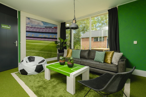 Woonkamer van de FC Mölke stadionlodge in Holiday Park Mölke, Nederland, met voetbalthema en groene accenten.
