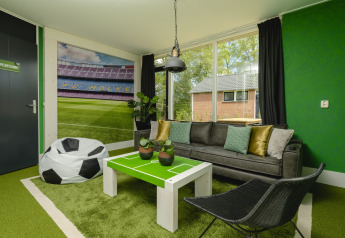 Living room of the FC Mölke stadium lodge at Holiday Park Mölke, Netherlands, with football-themed decor and green details.