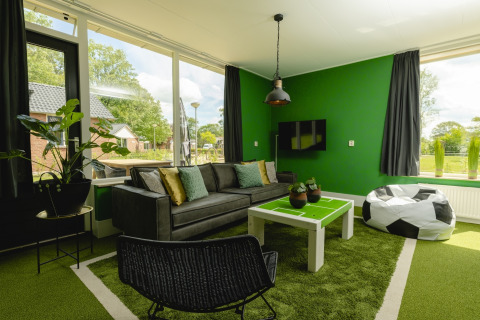 Woonkamer in FC Mölke stadion lodge bij Vakantiepark Mölke in Nederland met voetbalthema inrichting.