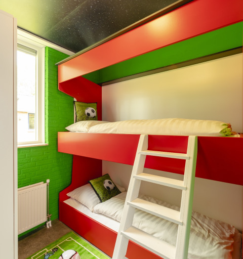 Lichte kamer met stapelbedden en voetbaldecoratie in het FC Mölke stadion van Holiday Park Mölke, Nederland.