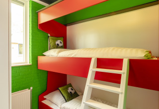 Lichte kamer met stapelbedden en voetbaldecoratie in het FC Mölke stadion van Holiday Park Mölke, Nederland.