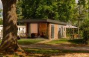 Modern tiny cabin at Holiday Park Mölke in the Netherlands, surrounded by greenery and outdoor seating.