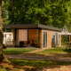 Moderna tiny cabin en Holiday Park Mölke en los Países Bajos, rodeada de árboles y área de descanso exterior.