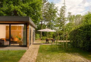 Cabaña moderna con grandes ventanales y terraza con sombrilla en Holiday Park Mölke, Países Bajos.