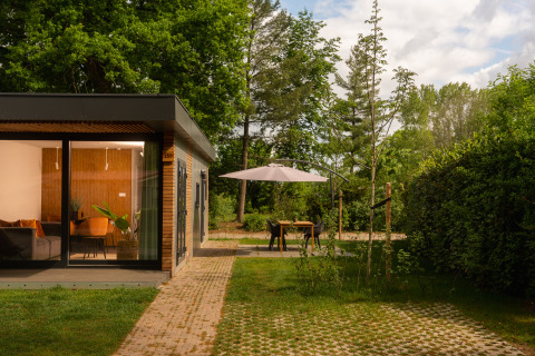 Moderna tiny cabin con ampie vetrate e terrazza con ombrellone presso Holiday Park Mölke nei Paesi Bassi.