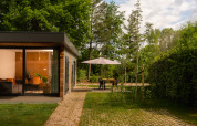 Moderna tiny cabin con ampie vetrate e terrazza con ombrellone presso Holiday Park Mölke nei Paesi Bassi.