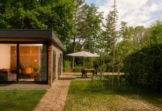 Moderne hytte med store vinduer og hyggelig terrasse i grønne omgivelser i Holiday Park Mölke, Holland.