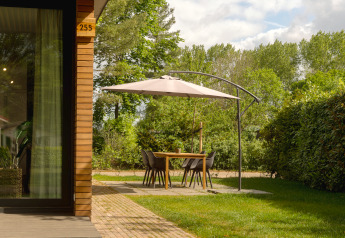 Essbereich im Freien mit Sonnenschirm an einer Holzhütte im Holiday Park Mölke, Niederlande.