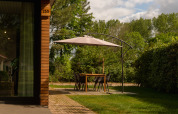 Zona de comedor exterior con sombrilla junto a una cabaña de madera en Holiday Park Mölke, Países Bajos.